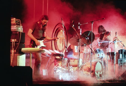 Pink Floyd playing on the stage surrounded with a smoke and illuminated with a red stage lights during the concert at Merriweather Post Pavilion, Columbia, Maryland in 1973.